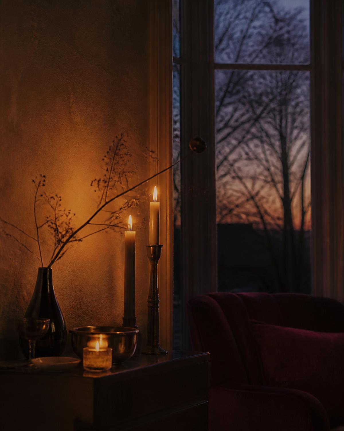 Candlelight glowing softly beside a window at dusk in a quiet warm room